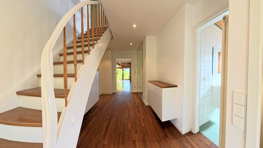 Heller Eingangsbereich mit Holzparkett und freitragender Treppe – Einfamilienhaus Marxzell-Burbach